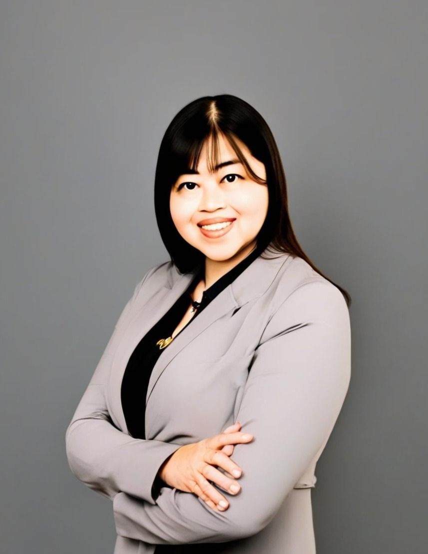A woman in a suit is standing with her arms crossed and smiling.