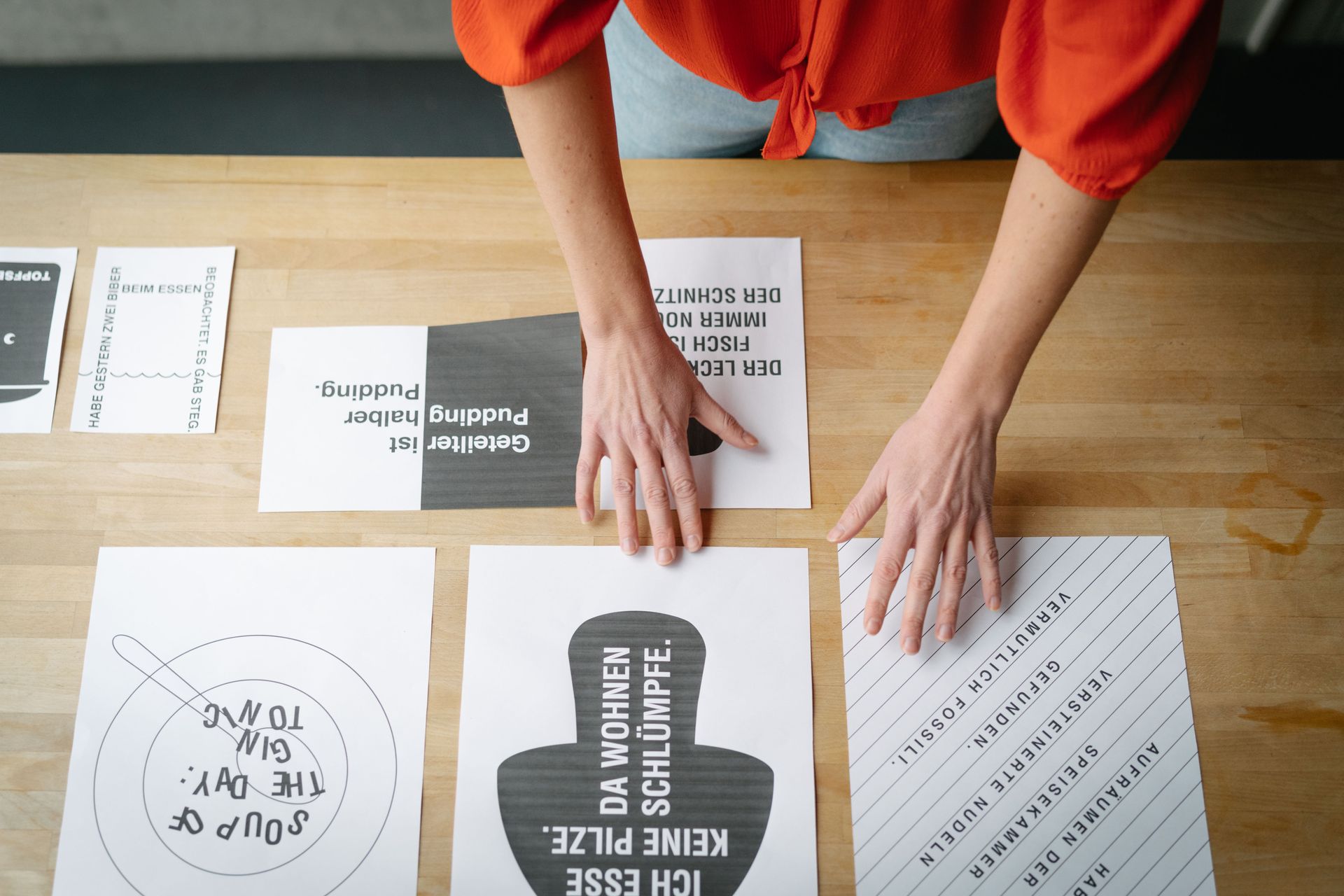 Ausschnitt von Leas Händen, wie sie ihre Skizzen in Grafik und Typografie sortiert.