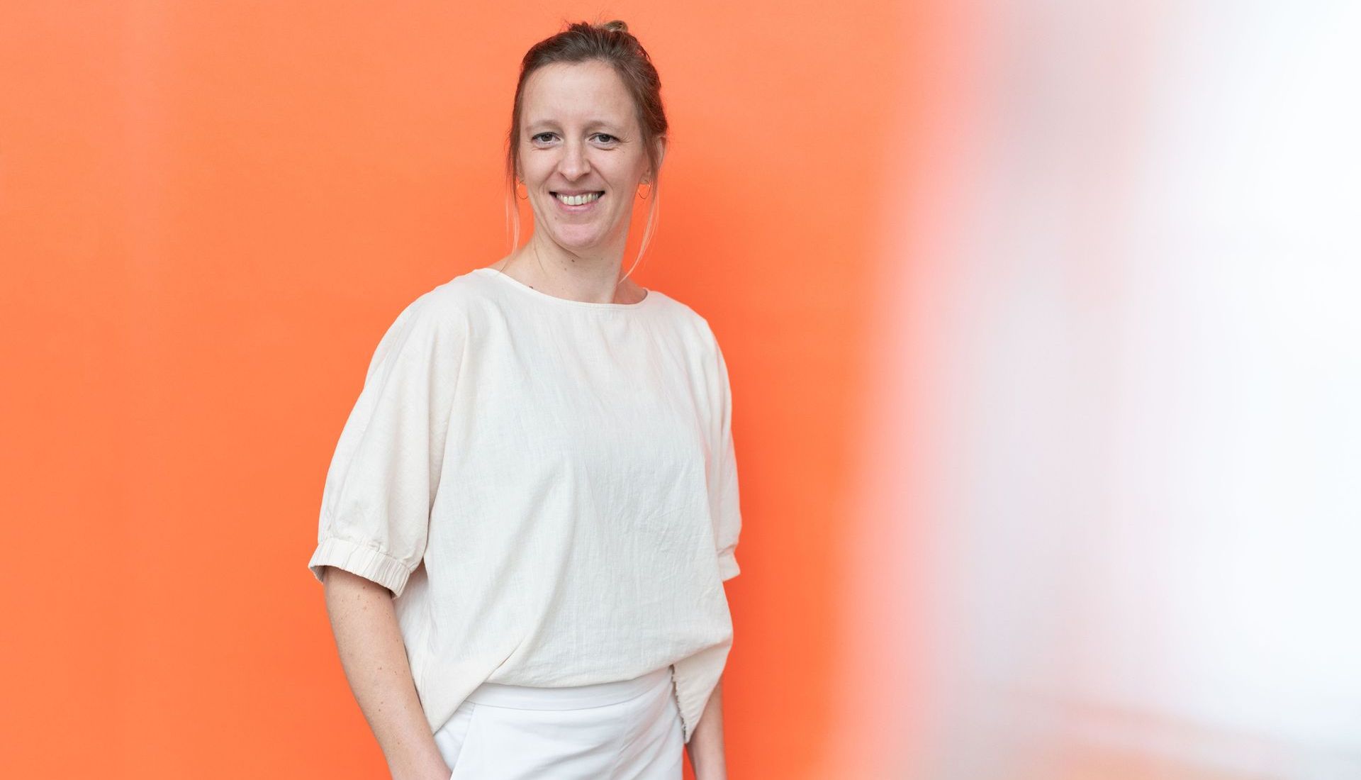 Profilbild von Lea vor dem orangenen Hintergrund – sie lächelt.