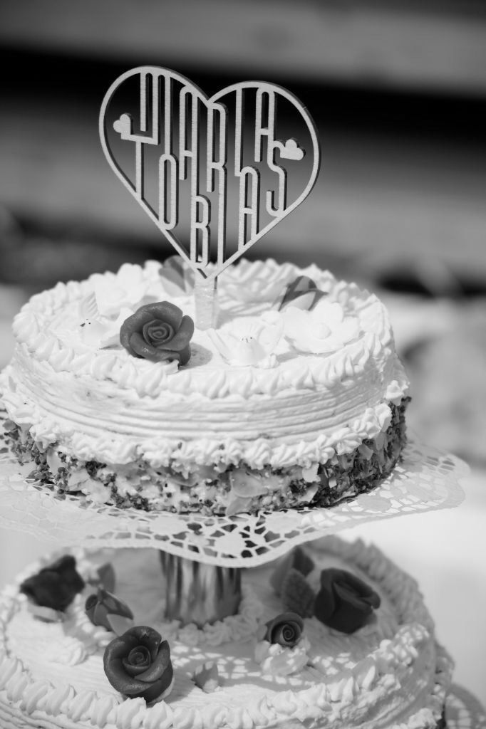 Cake Topper krönt auf einer 3-stöckigen Hochzeitstorte, abgebildet auf einem schwarzweißen Photo.