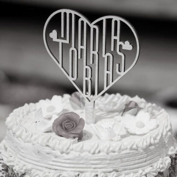 Cake Topper krönt auf einer 3-stöckigen Hochzeitstorte, abgebildet auf einem schwarzweißen Photo.