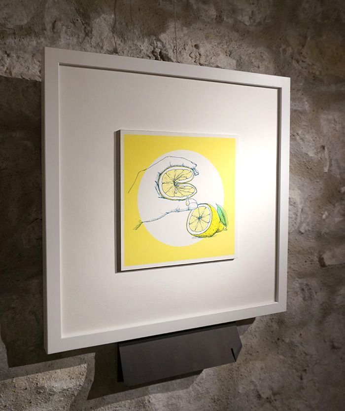 Eine Illustration im weißen quadratischen Bilderrahmen, es zeigt eine Zitrone das von einer Hand gefaltet wird. Ein zitronengelber Hintergrund unterstreicht das Bild.