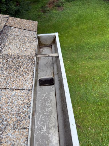 Roof edge gutter with a drainage opening beside a green lawn