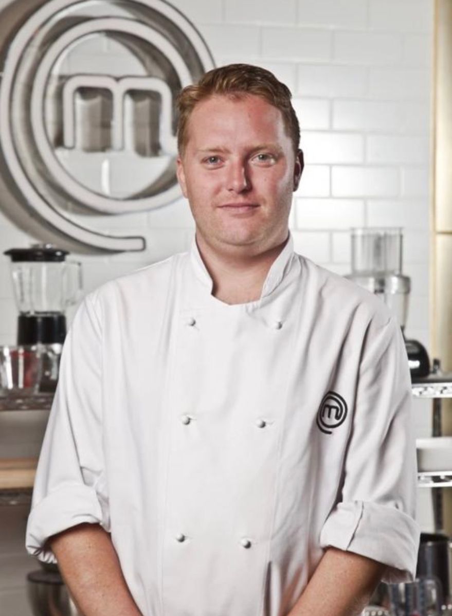  Photograph of Anton Piotrowski, with a Master Chef logo in the background, on the kitchen wall.