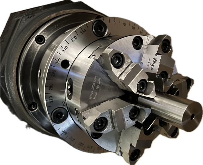 Metal lathe chuck with jaws gripping a cylindrical workpiece, shown close-up on a white background