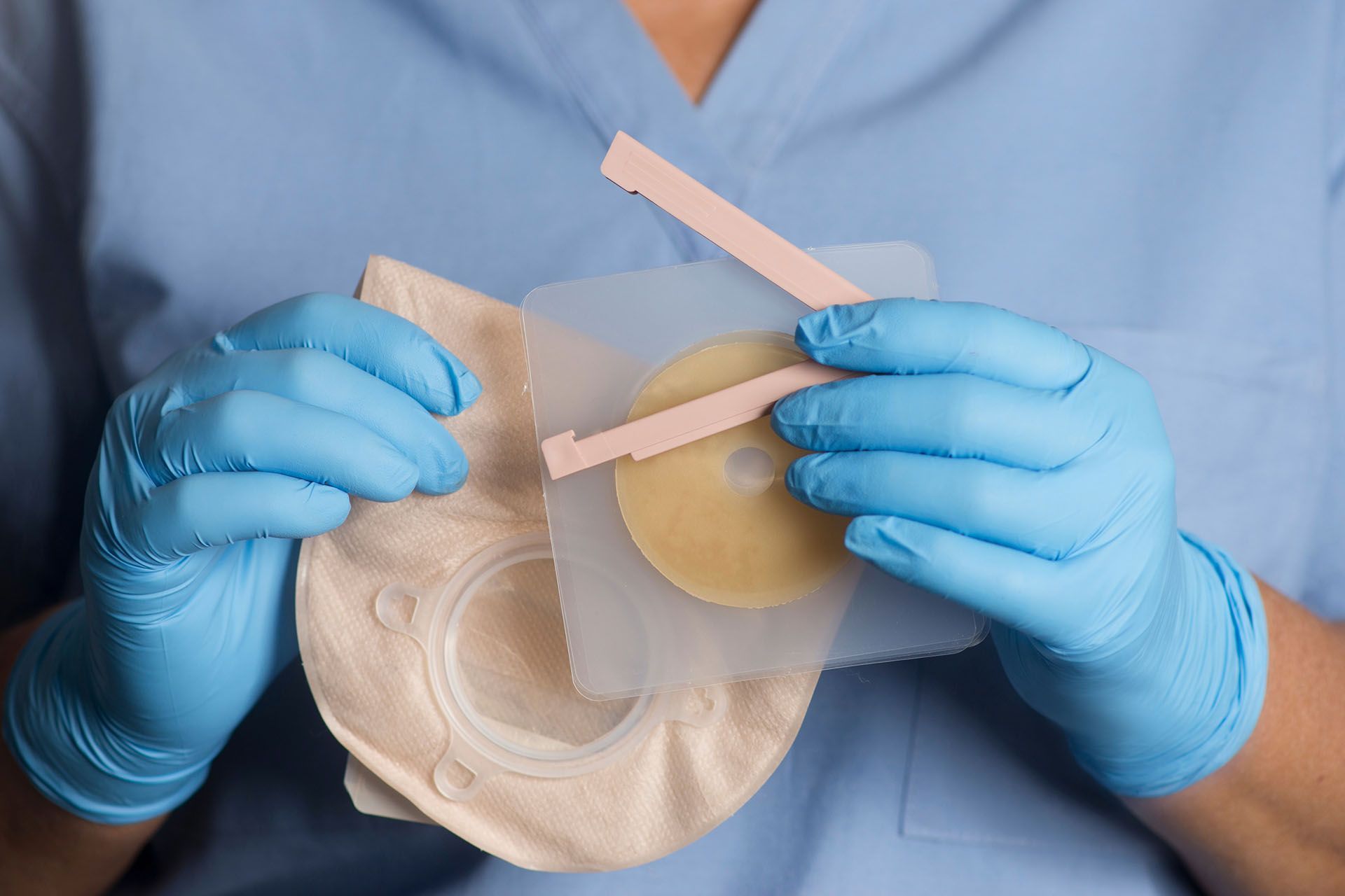 A person wearing blue gloves is holding a piece of plastic.