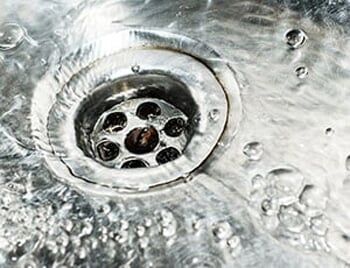 Stainless steel sink plug hole close up with water — Drain Cleaning in Coon Rapids, MN