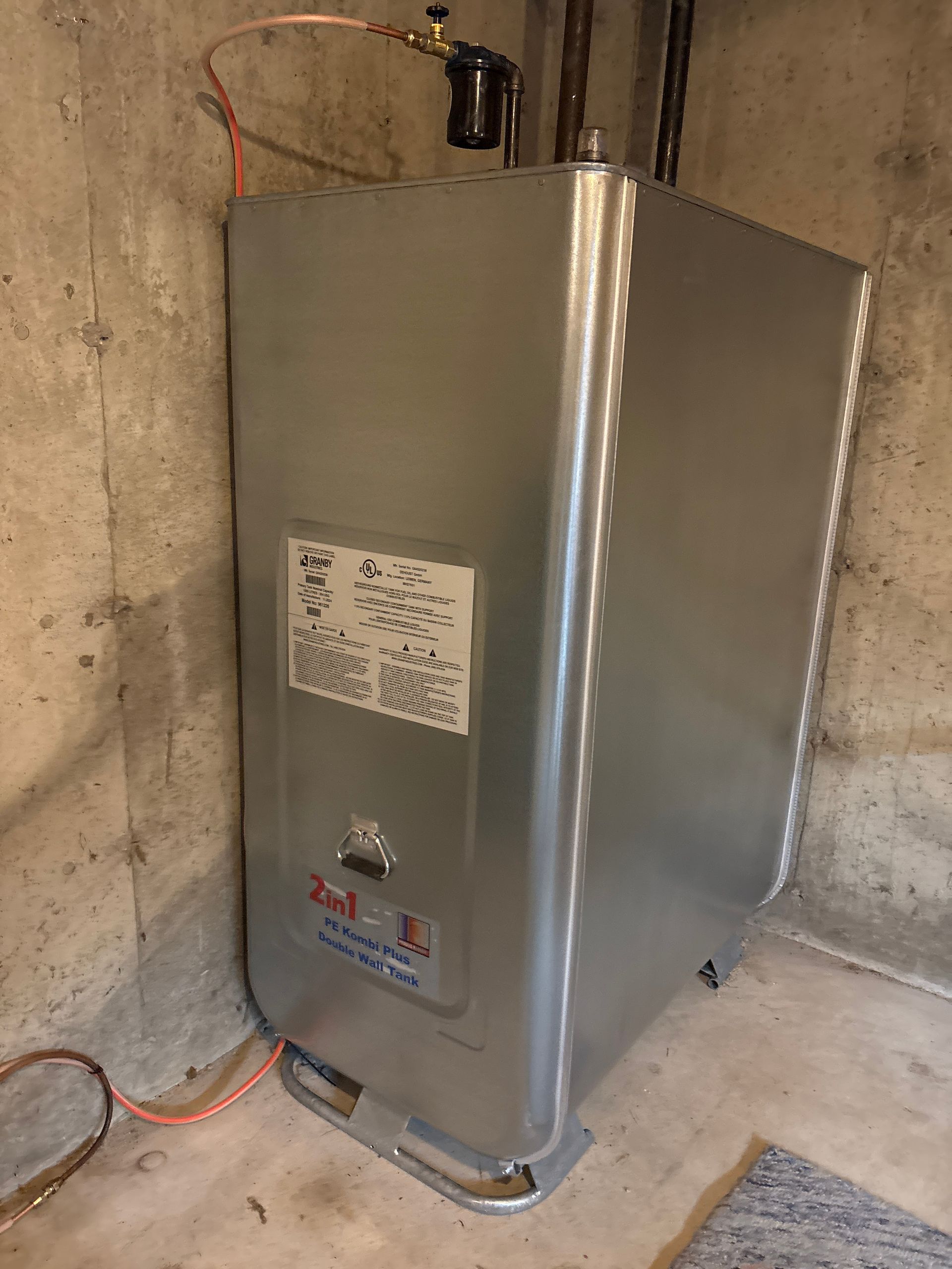 Silver oil tank in a concrete basement.