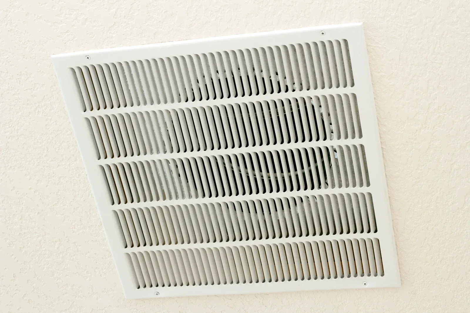 White rectangular air vent on a white ceiling.