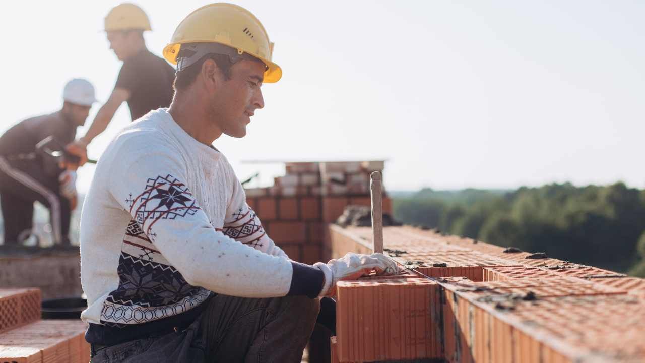 “Worker setting masonry blocks on a sunny job site during block and retaining wall services in Newport Beach, CA”