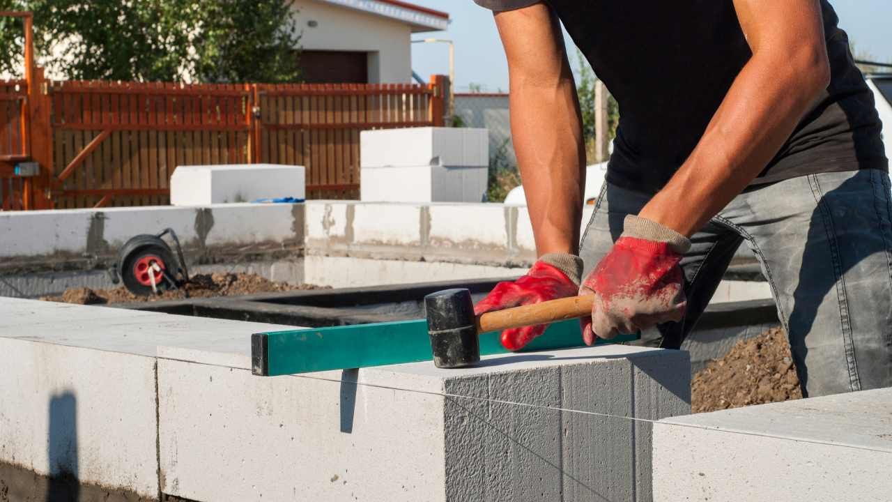 “Worker applying mortar along the top of a concrete block wall during block and retaining wall services in North Tustin, CA”