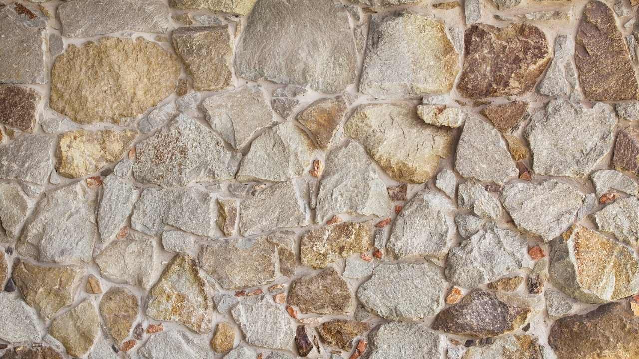 “Close-up of a natural stone wall with varied tan and gray rocks during block and retaining wall services in Orange, CA”