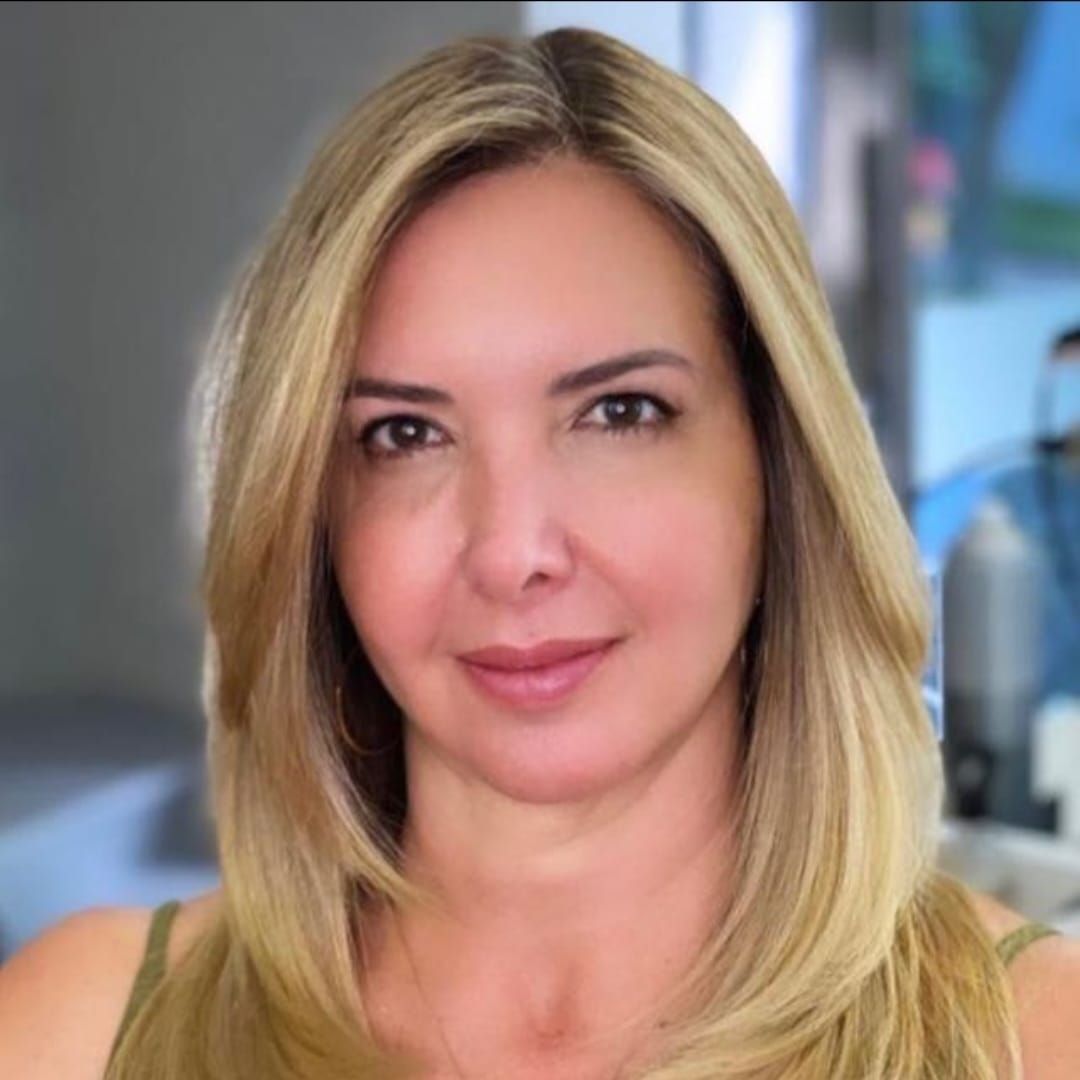 Uma mulher com longos cabelos loiros está sorrindo para a câmera.