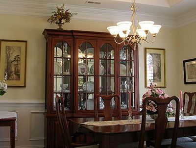 A dining room with a table , chairs , a hutch and a chandelier.