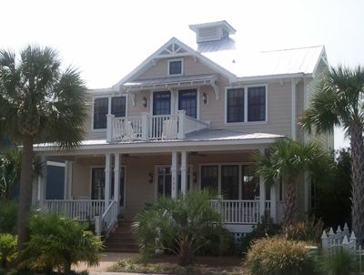A large house with a porch and palm trees in front of it