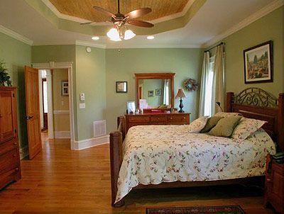 A bedroom with a bed , dresser , mirror and ceiling fan.