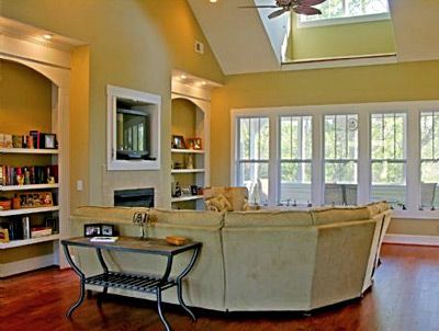A living room with a large sectional couch and a ceiling fan