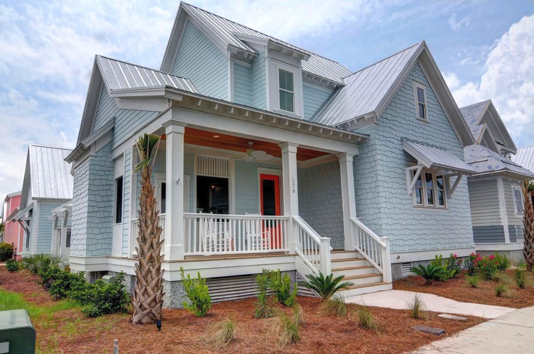 A blue and white house with a metal roof and a porch.