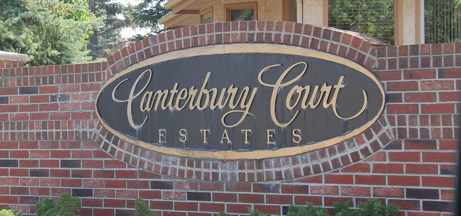 A sign for Canterbury court estates is on a brick wall
