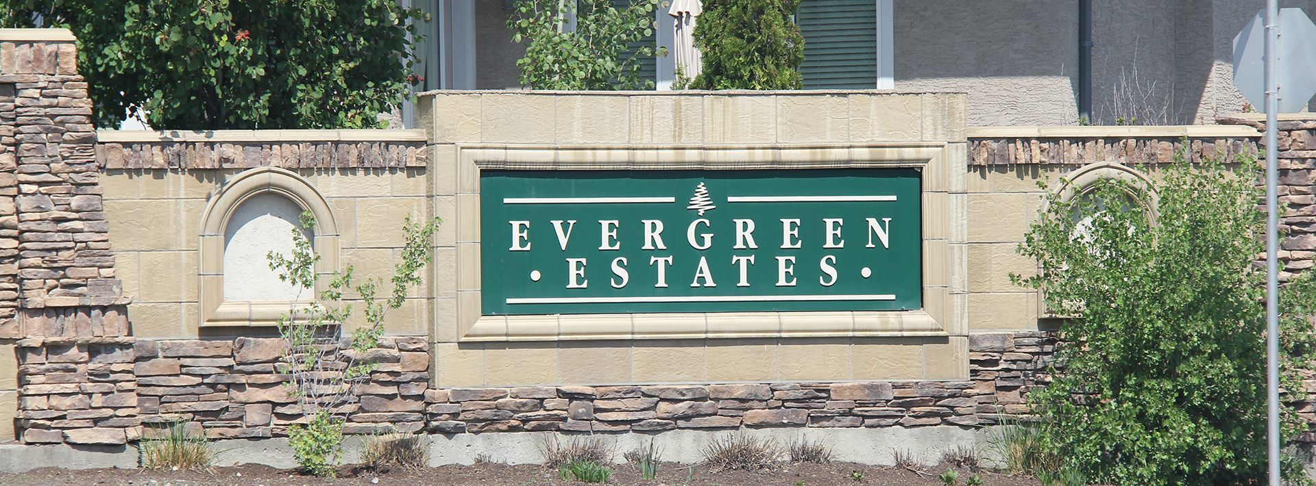 A sign for Evergreen Estates is on a stone wall