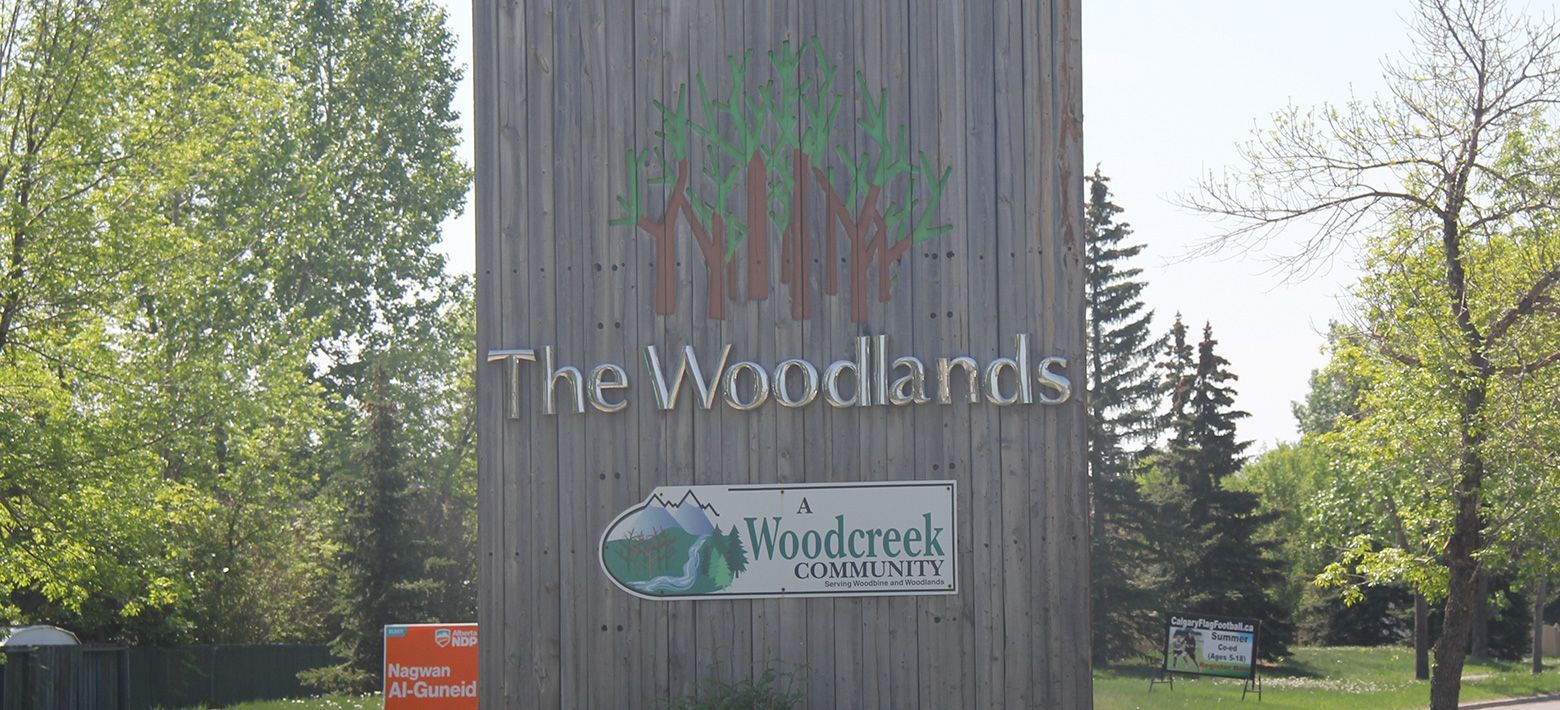 A wooden sign that says The Woodlands on it