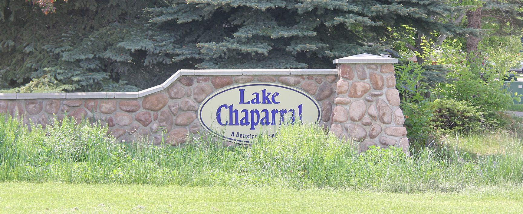 A stone wall with a sign that says lake chaparral