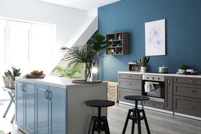 A kitchen with blue walls and gray cabinets and stools