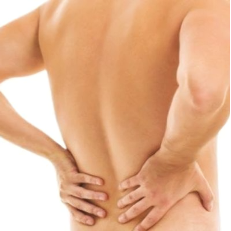 A shirtless man is holding his back in pain