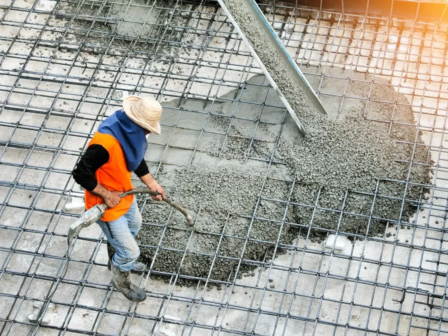 Worker standing on a rebar grid during a concrete slab pour.