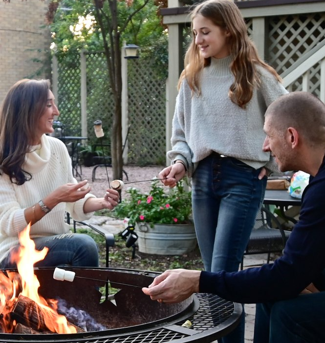A group of people are roasting marshmallows over a fire pit