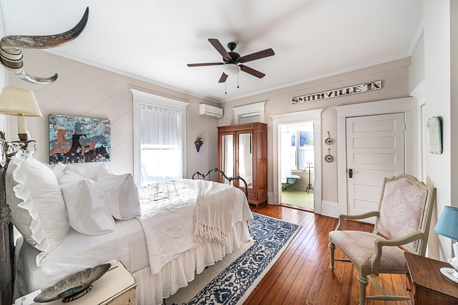 A bedroom with a large bed , chair , nightstand and ceiling fan.