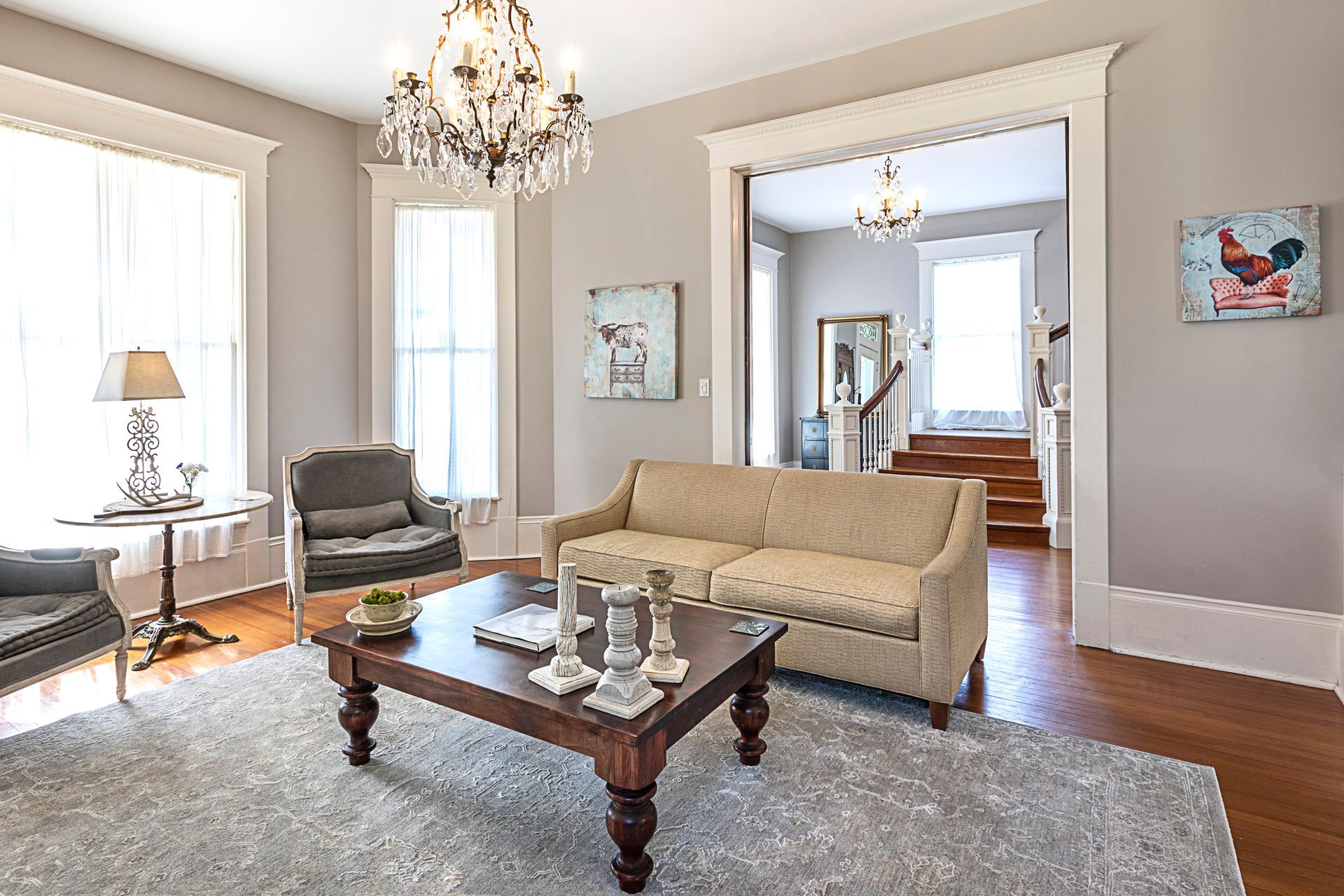A living room with a couch , chairs , coffee table and chandelier.