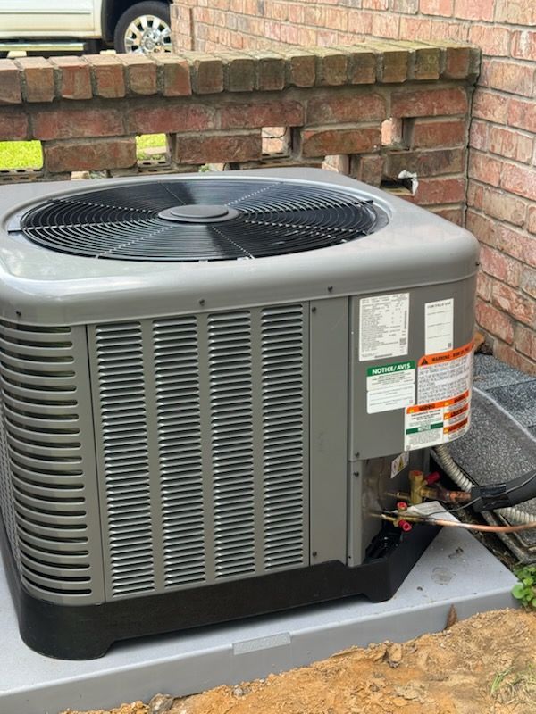 An air conditioner is sitting on the side of a brick building.