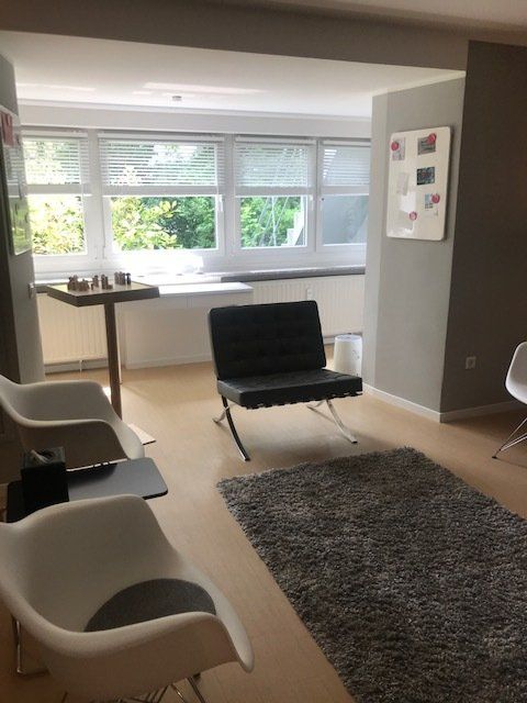 Ein Wohnzimmer mit weißen Stühlen und einem schwarzen Stuhl