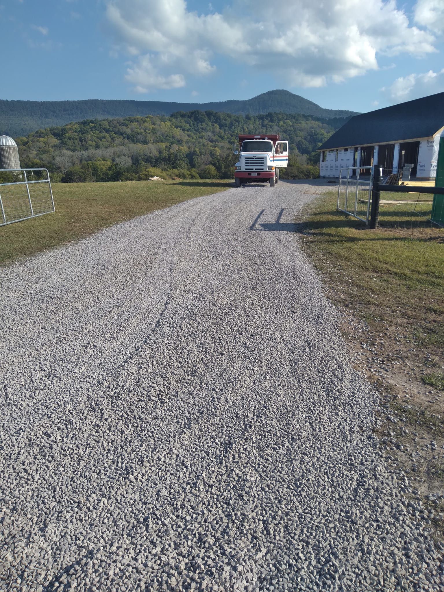 a truck is parked on the side of a gravel road .