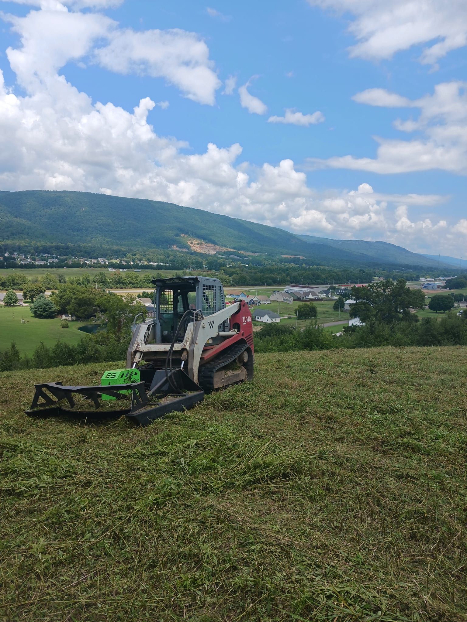 an excavator is in a field with mountains in the background .