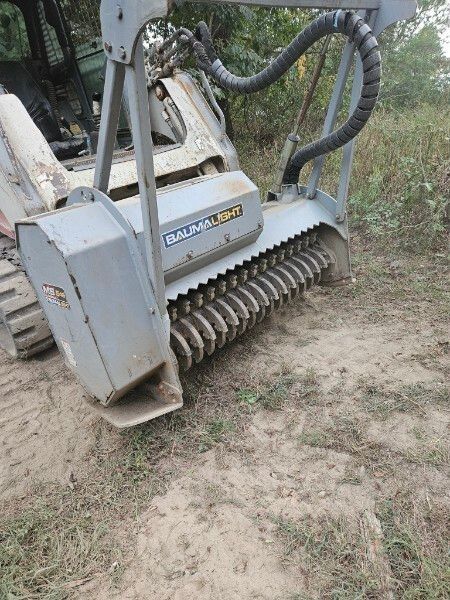 A large machine is sitting on top of a dirt field.