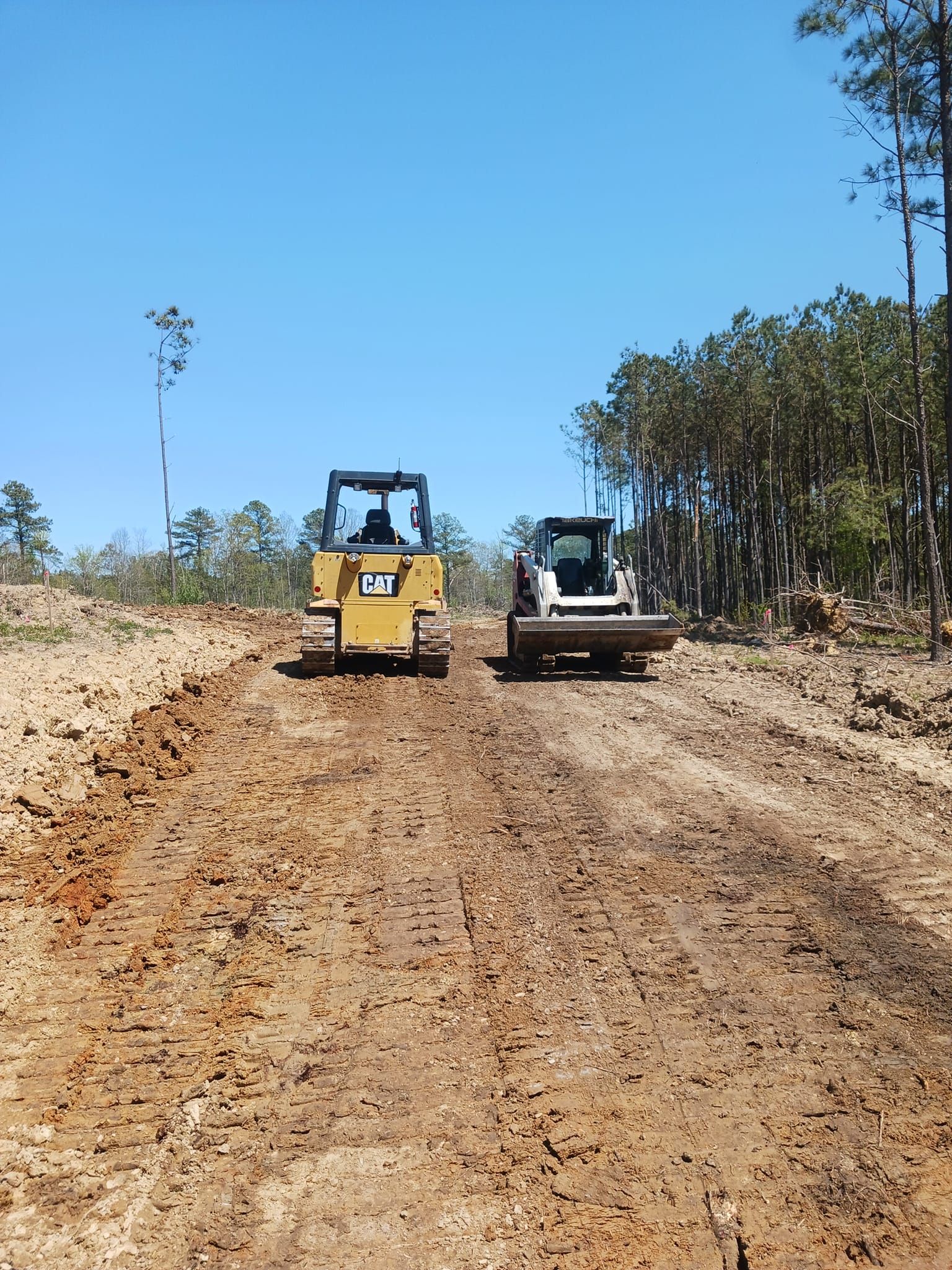 two bulldozers are driving down a dirt road .