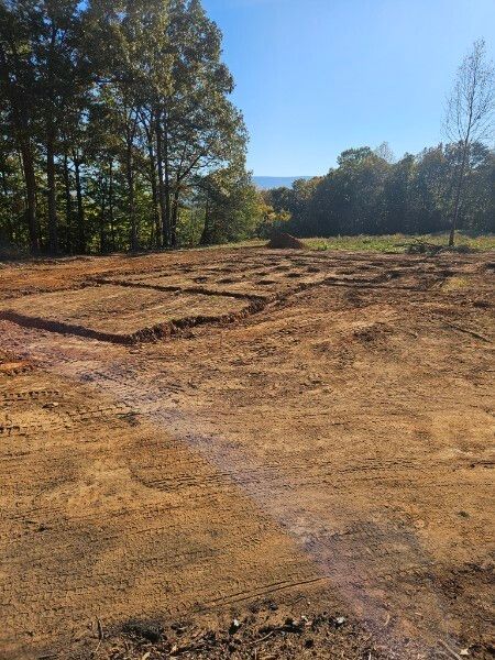 A large dirt field with trees in the background on a sunny day.