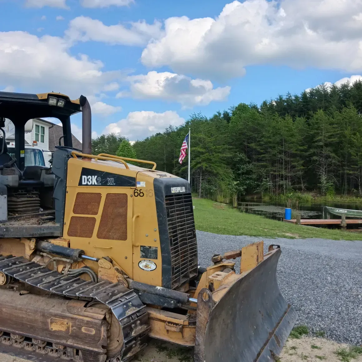 a bulldozer is parked on the side of a gravel road .
