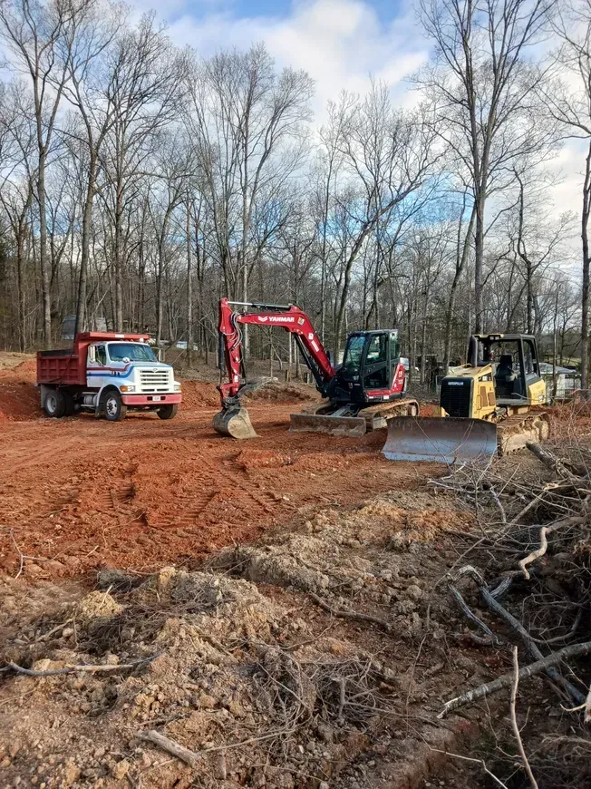 a dump truck is parked next to a bulldozer in a dirt field .