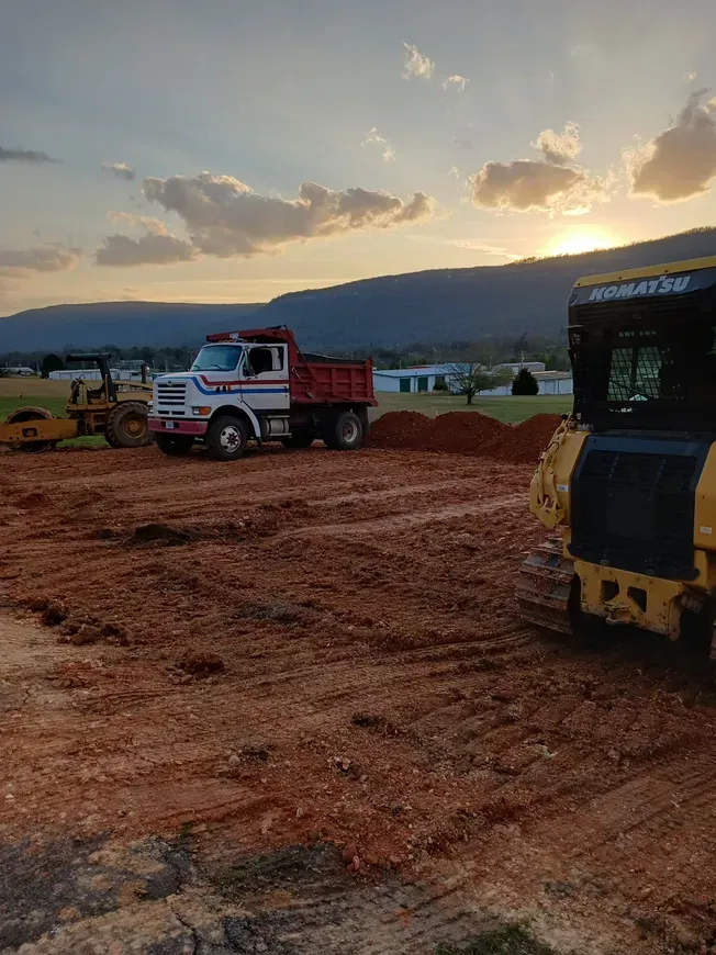 a dump truck and a bulldozer are parked in a dirt field .