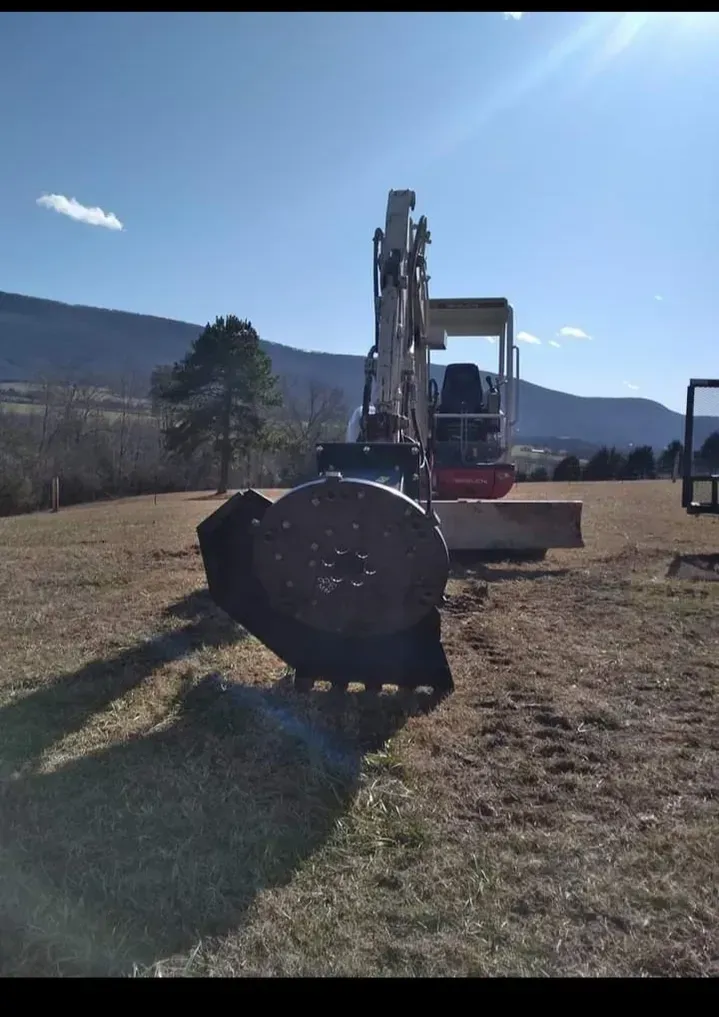 an excavator is sitting in a field with mountains in the background