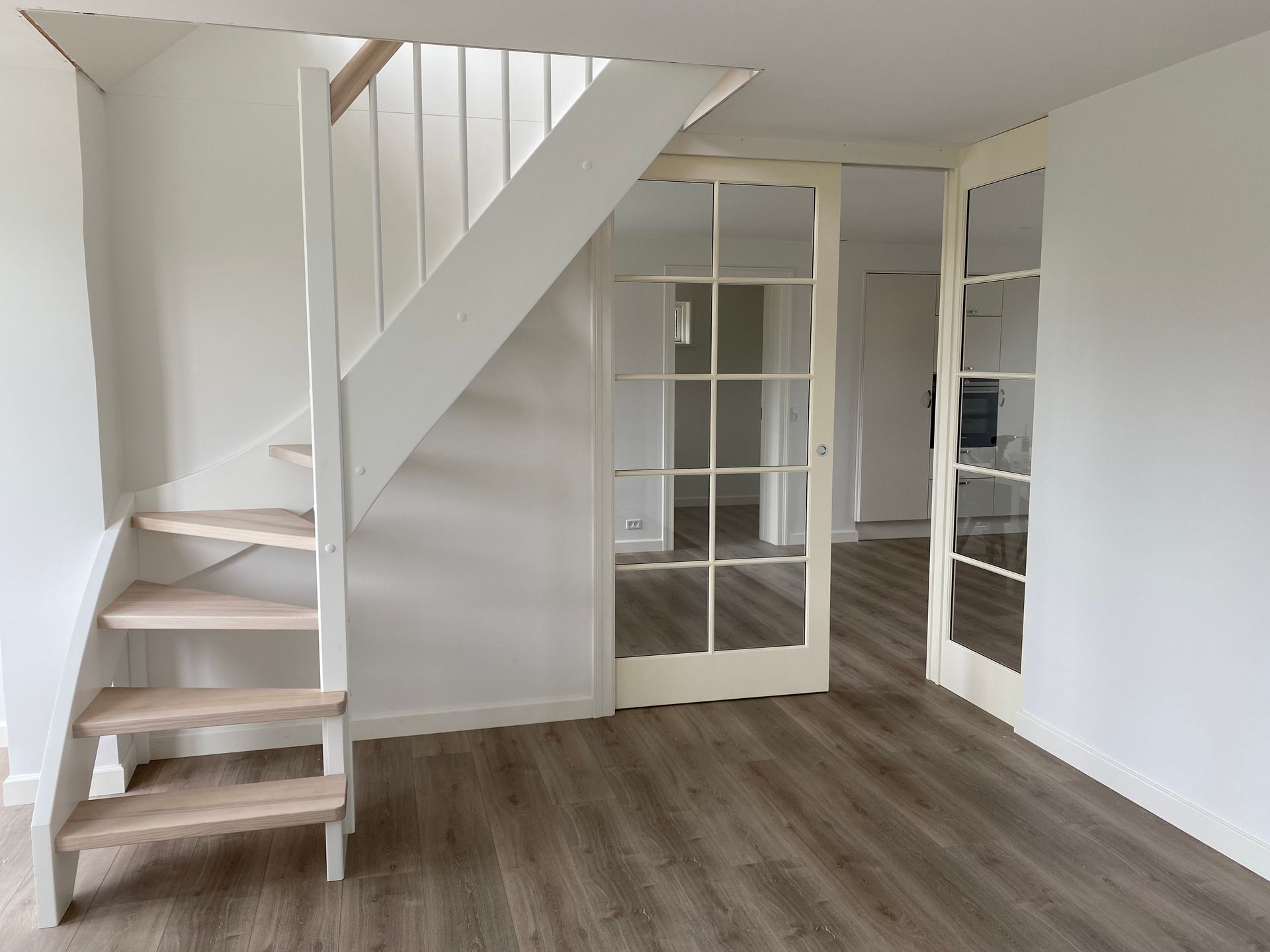 Foto af lyst rum med trappe og sprosset glasdør