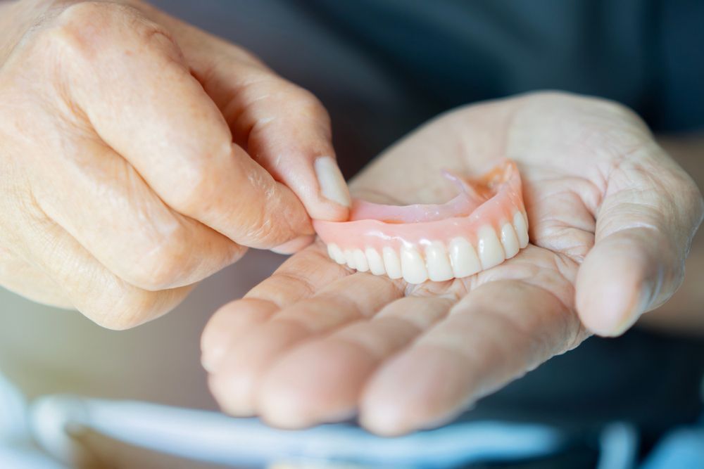 A person is holding a denture in their hands.