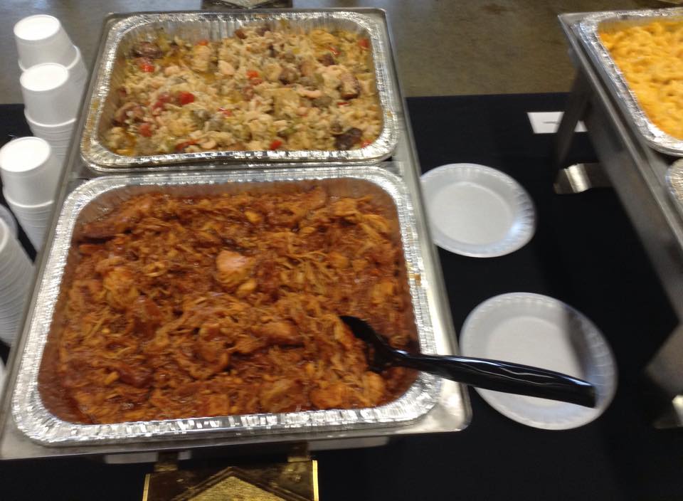 Two trays of food on a table with plates and cups