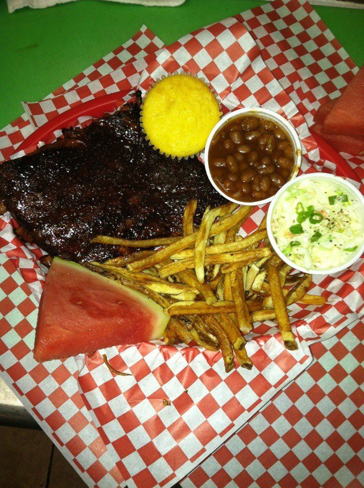 A plate of food with ribs french fries beans and cornbread
