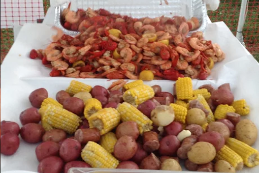 A table topped with potatoes , corn on the cob , and shrimp.