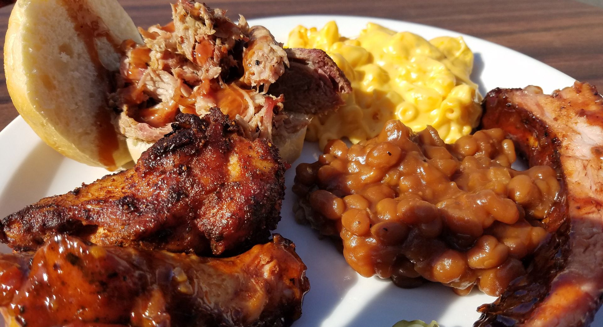 A white plate topped with meat beans and corn on the cob