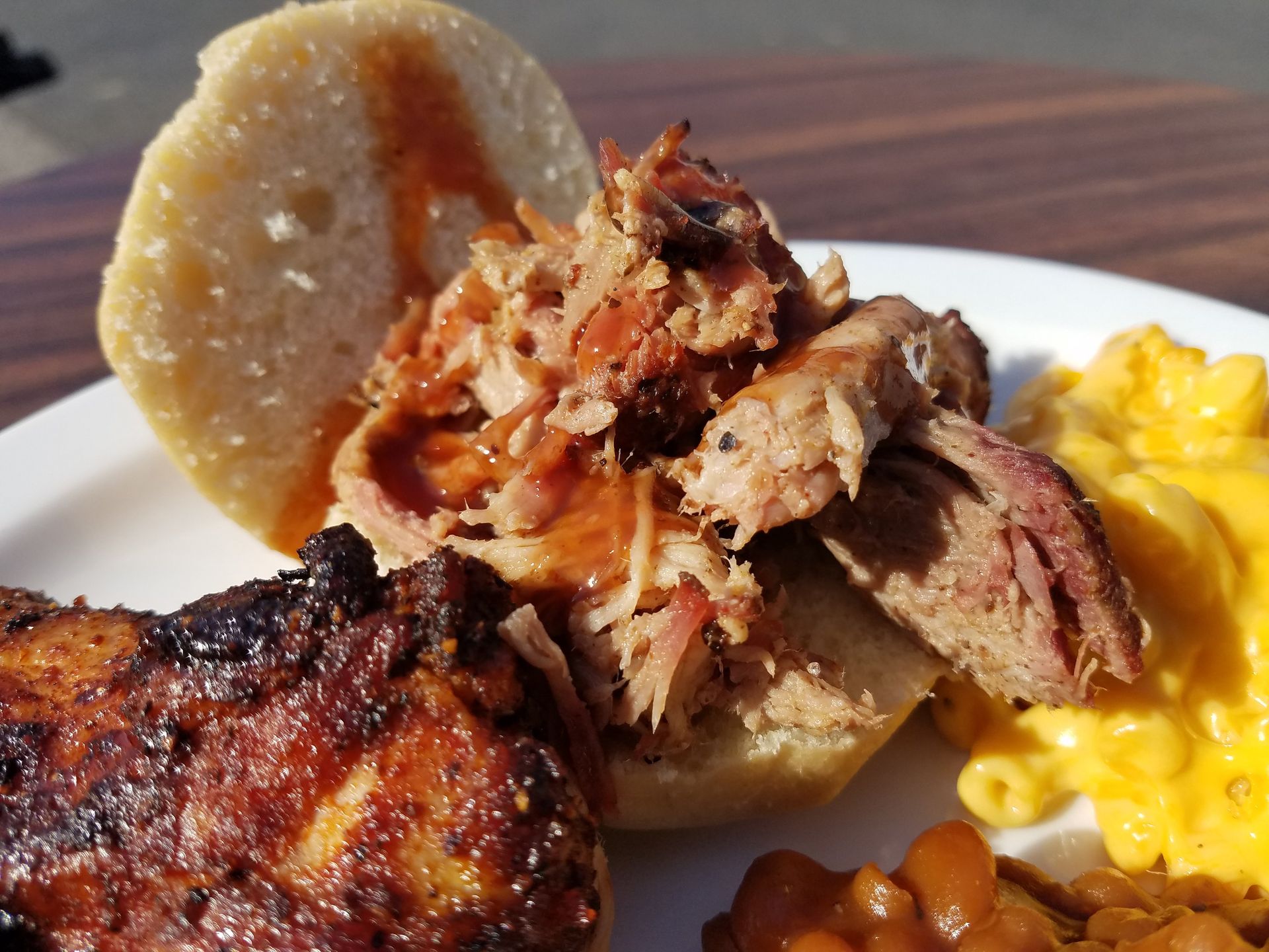 A close up of a plate of food with meat , macaroni and cheese and beans.